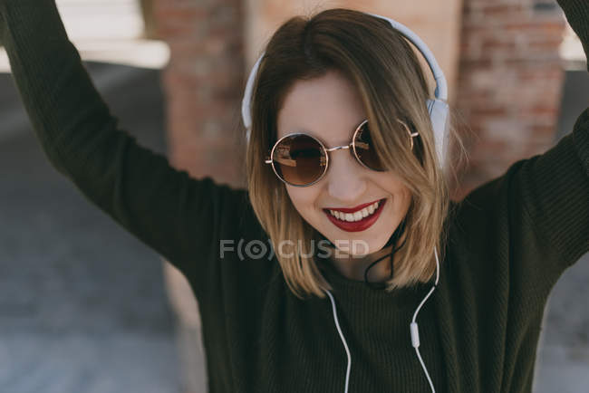 Chica en auriculares posando con los brazos levantados - foto de stock