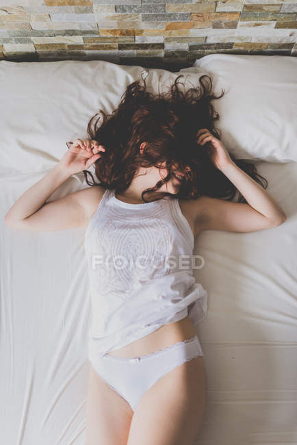 Mulher com cabelo no rosto deitado na cama — Fotografia de Stock