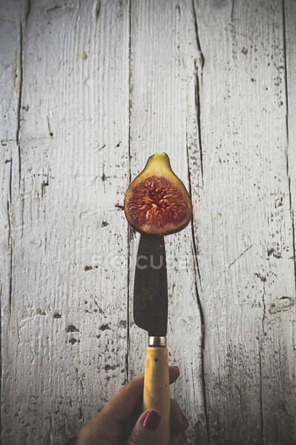 Gros plan du couteau à main femelle avec la moitié de figue fraîche — Photo de stock