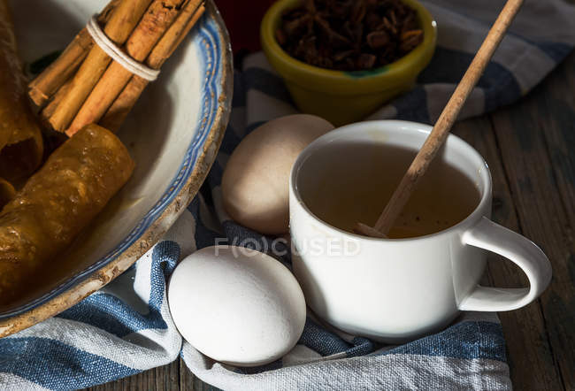 Close up view of eggs and cup with honey spoon on rural towel — Stock Photo
