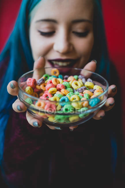Close up view of blue haired girl holding bowl of colorful cereals — Stock Photo