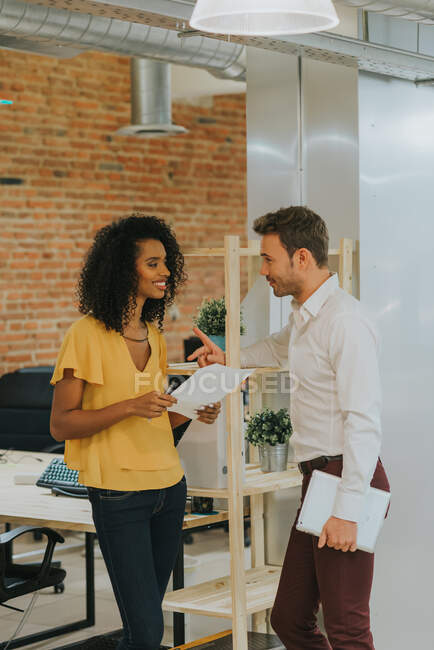 Talking woman and man standing in office. Vertical indoors shot — Stock Photo