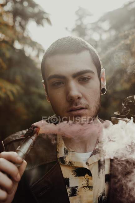 Uomo in posa con candela fumogena nei boschi — Foto stock
