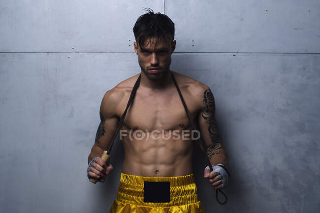 Cool fighter posing with jumping rope around his neck. Horizontal indoors shot. — Stock Photo