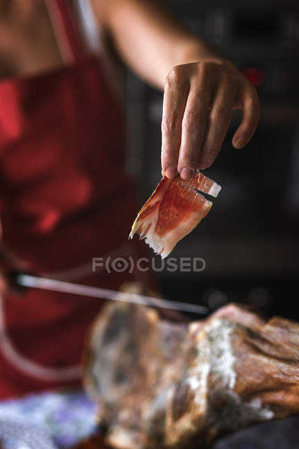 Hand holding Serrano ham slice — Stock Photo