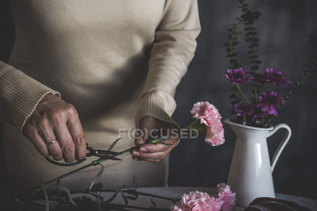 Seção média de florista fêmea cortando haste da flor com tesoura — Fotografia de Stock
