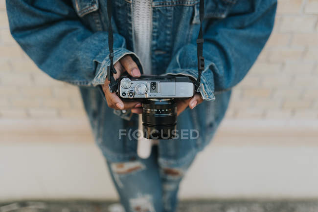 High angle view of female wearing holding analog camera and leaning on brick wall — Stock Photo