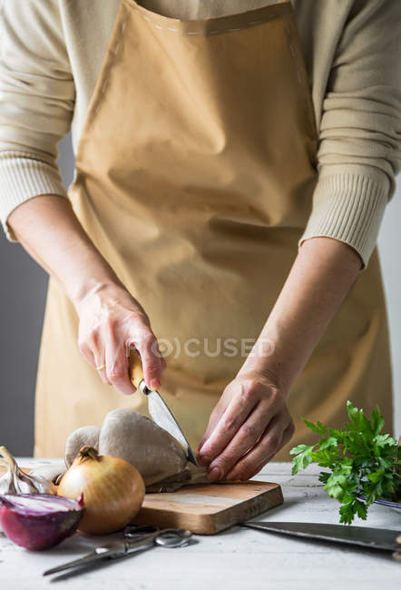 Seção média de fêmeas cortando cogumelos pleurotus em tábua de madeira na mesa da cozinha — Fotografia de Stock
