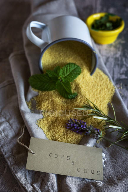 Stillleben verschütteter Couscous-Zutaten auf dekorativer Serviette mit Pappschild — Stockfoto