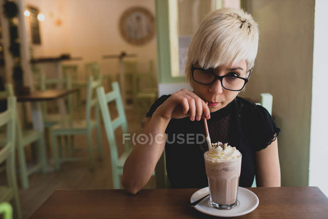 Дівчина в окулярах п'є молоко трясе — стокове фото