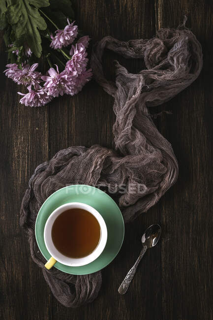 Xícara de chá com fundo floral com tulipas vermelhas e brancas e margaridas, e folhas verdes em fundo marrom. Deitado plano, vista superior — Fotografia de Stock