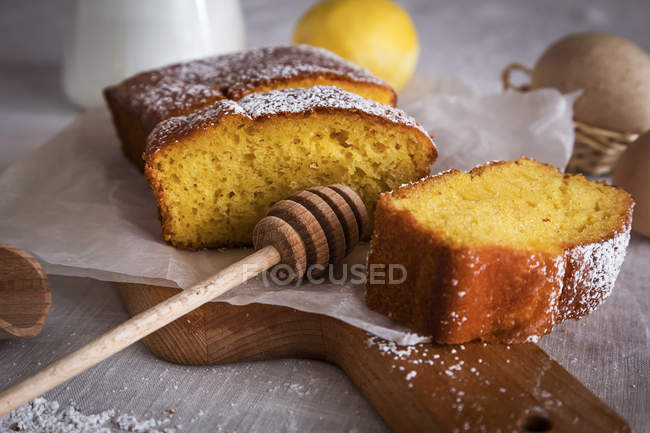 Nature morte de tranches de gâteau au citron à bord avec cuillère à miel — Photo de stock