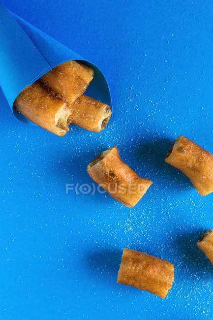 Churros in paper cone on blue — Stock Photo