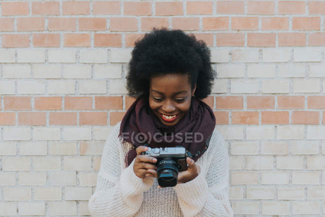 Ritratto di ragazza sorridente con macchina fotografica su muro di mattoni su sfondo — Foto stock