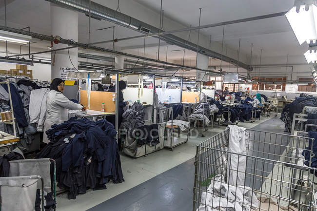 TANGIER, MARRUECO- 18 de abril de 2016: Máquinas de coser industriales y maquinistas trabajando en línea - foto de stock