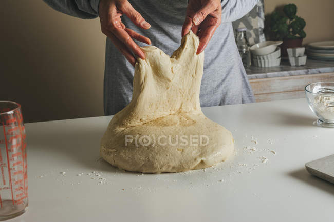 Female hand kneading and shaping a risen dough — Stock Photo