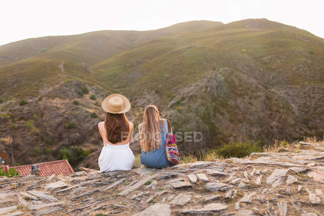 Девушки сидят вместе на горном краю — стоковое фото