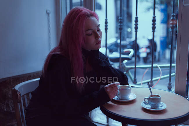 Schläfrige, erschöpfte Frau sitzt im Café und trinkt Kaffee. — Stockfoto