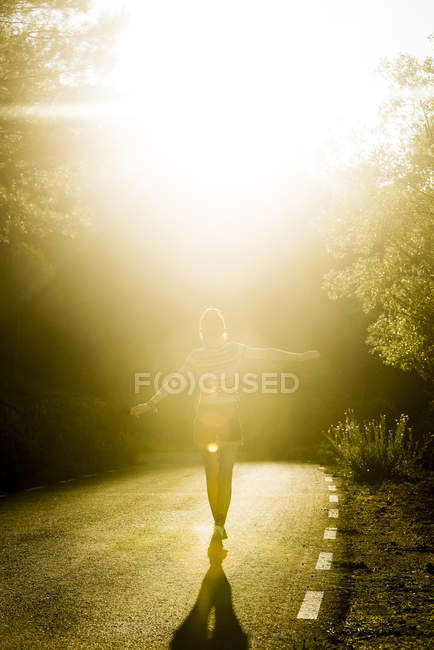 Girl walking on sunny road — Stock Photo