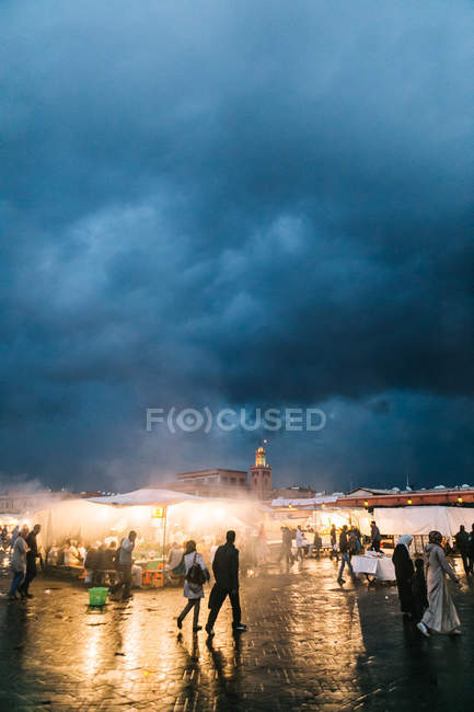 Gente caminando en el mercado bajo un duro paisaje nublado - foto de stock