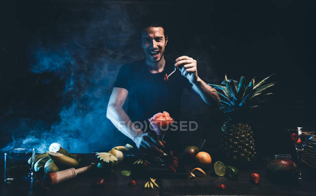 Hombre preparando cóctel con fresa - foto de stock