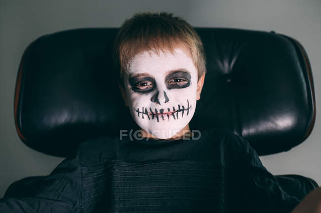Niño con la cara del cráneo pintura mirando a la cámara - foto de stock