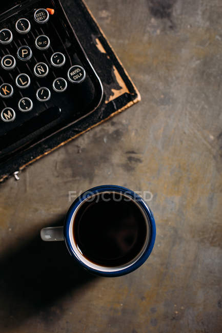 Taza con café y máquina de escribir - foto de stock