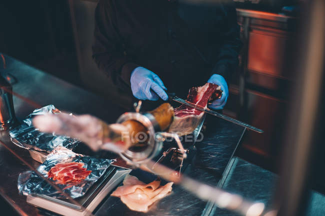 Crop man cortando delicioso jamon — Fotografia de Stock