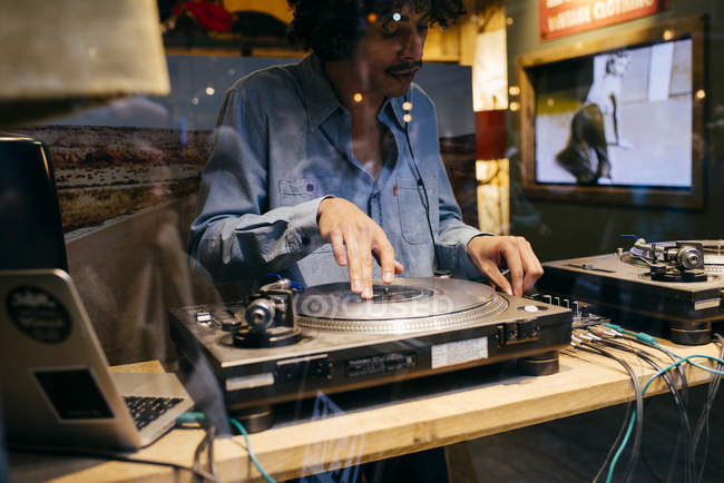 LONDRES, ROYAUME-UNI - 4 MAI 2017 : Tourné à travers un verre d'homme debout en studio jouant à la console DJ — Photo de stock