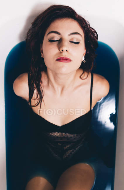 Девушка расслабляется в ванне ярко-голубой воды — стоковое фото