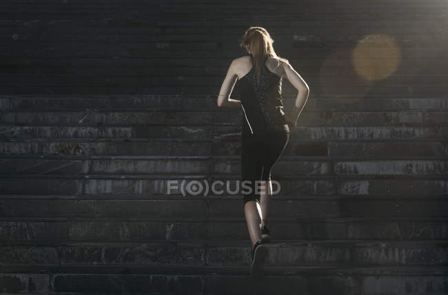 Sportive girl running up stairs — Stock Photo
