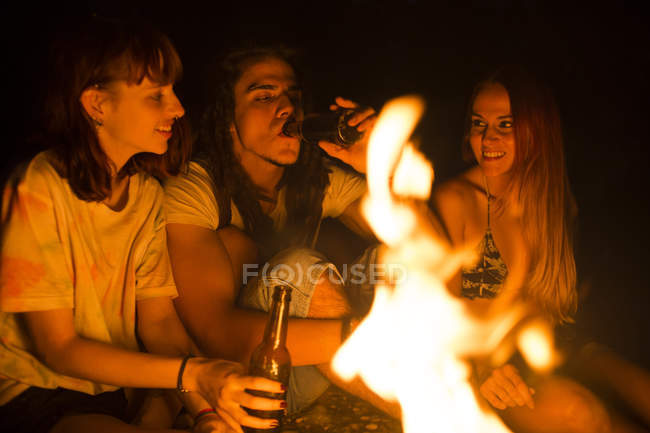 Freunde trinken Bier am Lagerfeuer — Stockfoto