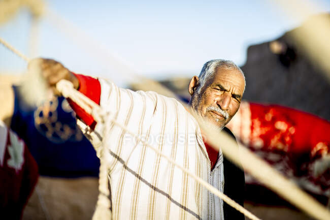 Portrait of serious Arabian man standing and holding the rope of  tent. — Stock Photo