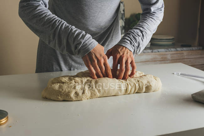 Жінка масажує хліб: складає тісто на третину і запечатує — стокове фото