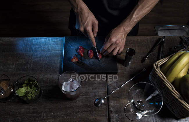 Mãos masculinas cortando morangos — Fotografia de Stock