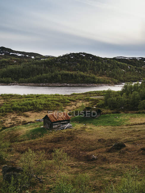 Покинутий сільський будинок на березі гір річки — стокове фото