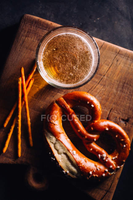 Copo de cerveja com algum aperitivo como pretzels — Fotografia de Stock
