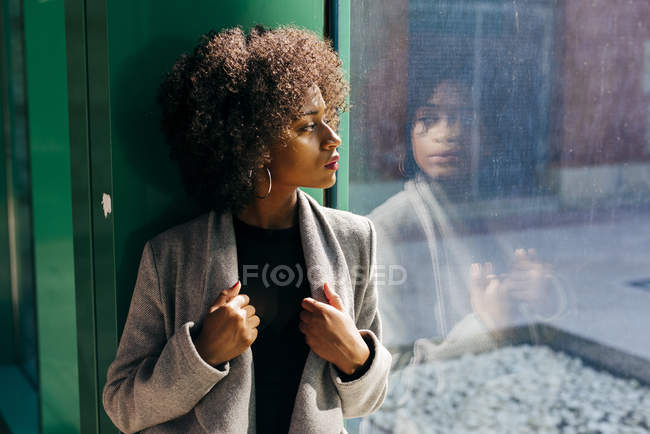 Mulher posando perto da janela e olhando para o lado — Fotografia de Stock