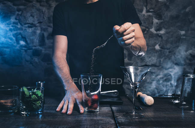 Mains masculines mettant des igridients dans un verre à cocktail — Photo de stock