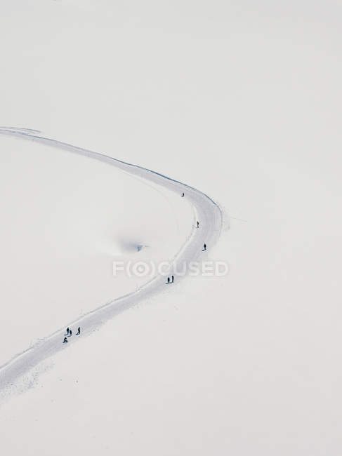 Luftaufnahme von Touristen, die in Reih und Glied auf einer Schneepiste laufen — Stockfoto
