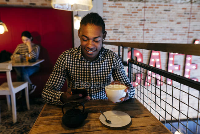 Чоловік використовує смартфон у кафе — стокове фото