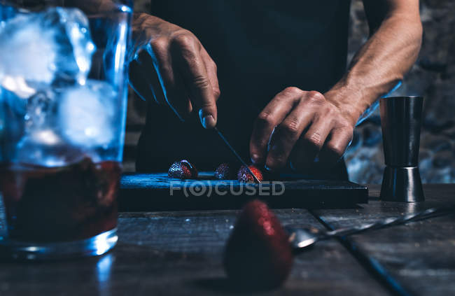 Male hands slicing strawberries — Stock Photo