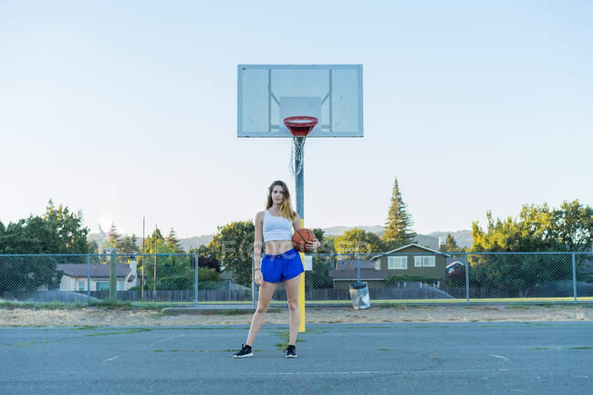 Mujer elegante celebración de baloncesto naranja en el campo de deportes - foto de stock