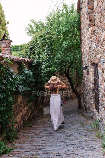 Mujer caminando y ajustando sombrero - foto de stock