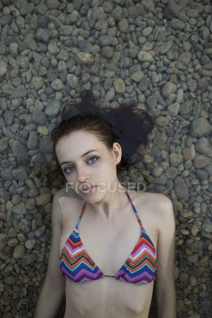Girl lying on pebble and looking at camera — Stock Photo