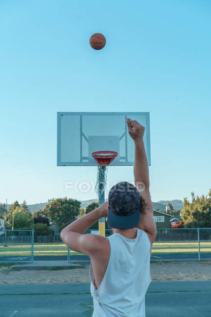 Homem jogando bola de basquete no ringue — Fotografia de Stock
