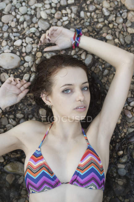 Girl lying on pebble and looking at camera — Stock Photo
