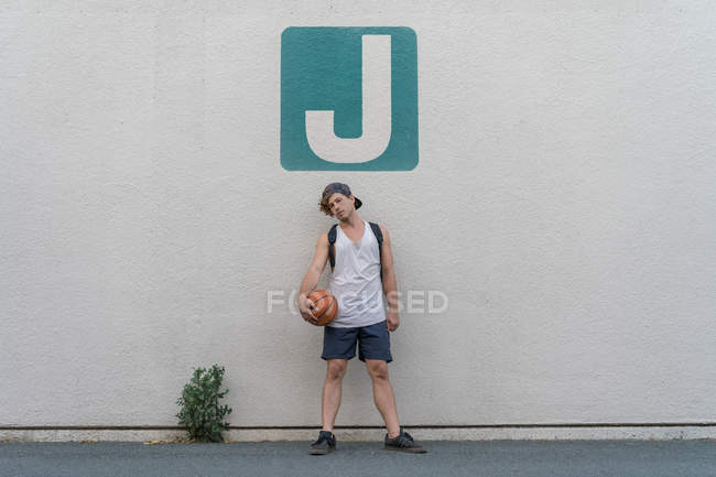 Mann mit Basketball posiert in der Nähe der Mauer — Stockfoto