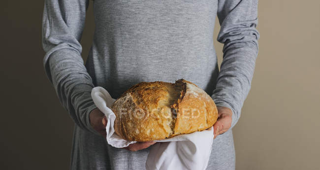Mãos femininas segurando um pão rústico — Fotografia de Stock