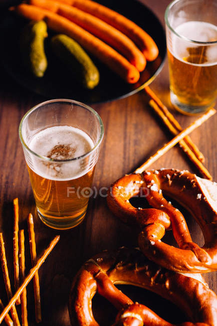 Copo de cerveja com algum aperitivo como pretzels — Fotografia de Stock